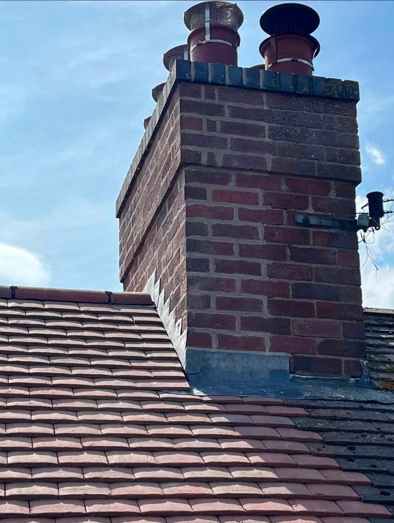 Lead flashing sealing the base of a chimney on a roof