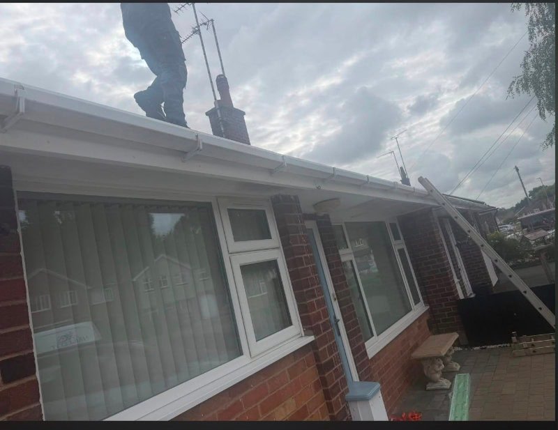 A roofer fitting new guttering along the roofline of a bungalow in Leicester